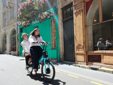 a woman riding a bike next to a woman in a white shirt